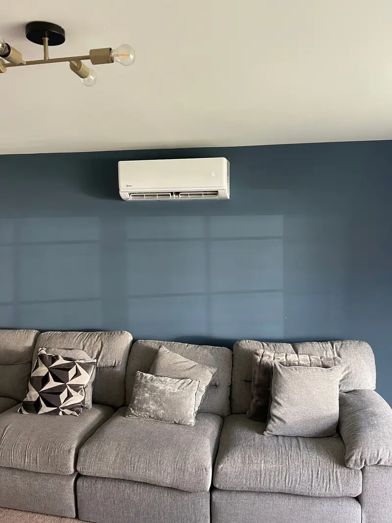 Air conditioning in Acomb, York Wall-mounted air conditioning unit on a navy feature wall above a sofa, typical of a living room in an Acomb semi