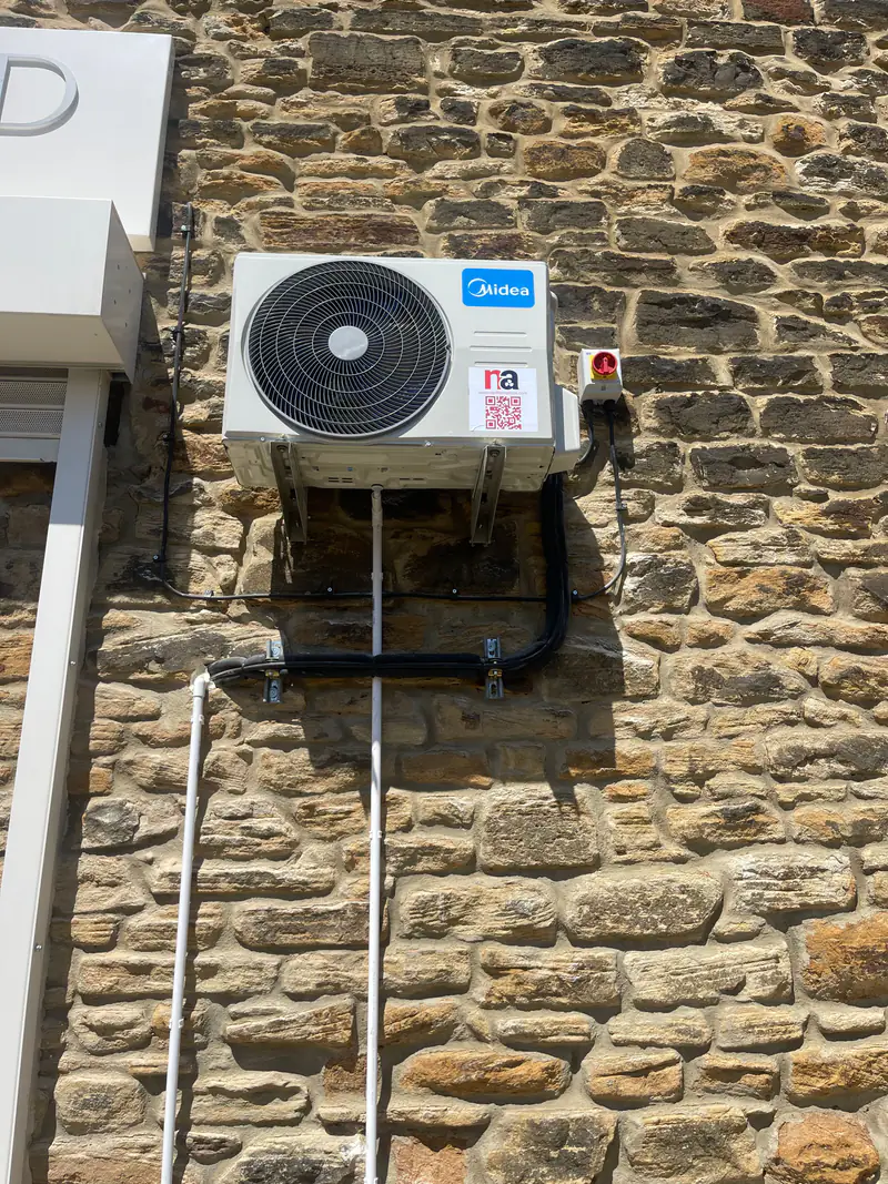 Air conditioning repairs in York Outdoor air conditioning unit on wall brackets with insulated pipework and an isolator switch, ready for repair diagnosis