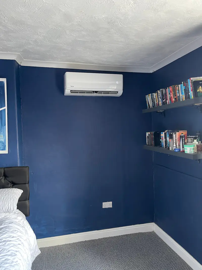 Bedroom air conditioning in Stamford Bridge Air conditioning unit in a navy-painted bedroom with bookshelves in a Stamford Bridge home