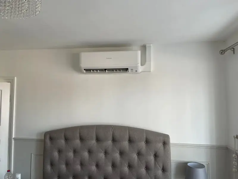 Bedroom air conditioning in Wetherby Wall-mounted air conditioning unit above a grey buttoned headboard in a Wetherby bedroom